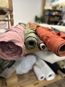 Close up assorted rolls of white, beige and brown flax linen fabric and canvas textile on retail market stall, high angle view